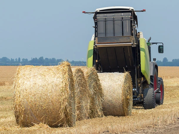 Tractor and round baler discharging straw bales