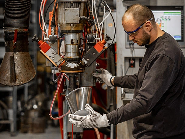 Ein Mitarbeiter arbeitet an einer Maschine in der Kunststofftechnik.