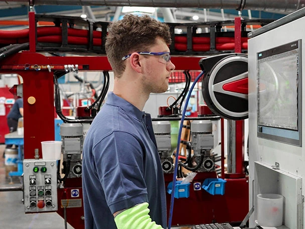 Ein Auszubildender Maschinen- und Anlagenführer mit Schwerpunkt Metall- und Kunststofftechnik arbeitet an einer Maschine.