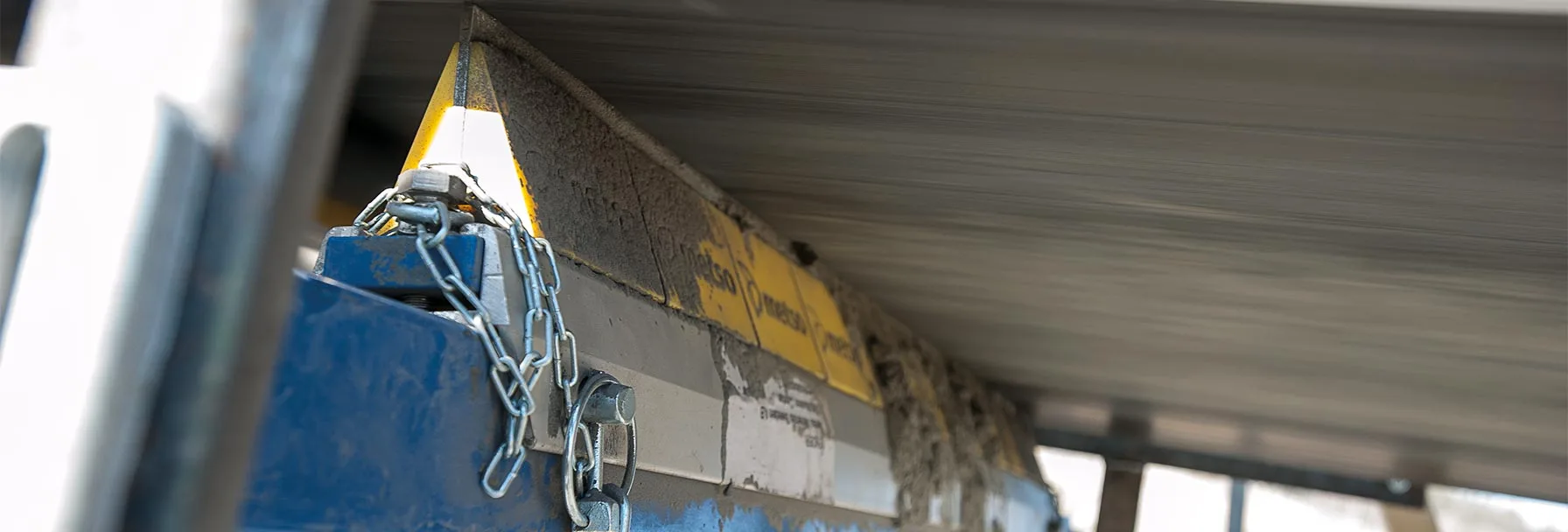 Fördergurtreinigungssysteme Secondary belt cleaner scraping dirt from a rubber conveyor belt